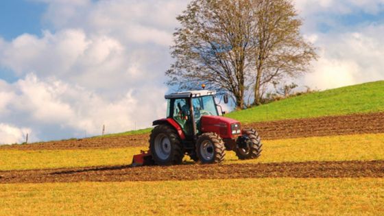 Tractor rojo arando un campo
